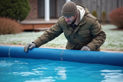 Homme en parka posant une couverture solaire sur la piscine