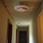 Détecteur de fumée au plafond d'un appartement en location avec voyant rouge allumé