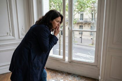 Femme parisienne regardant une vitre brisee dans son appartement