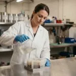 Technicienne versant du silicone de moulage liquide dans un moule en atelier industriel