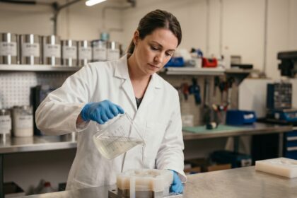 Technicienne versant du silicone de moulage liquide dans un moule en atelier industriel